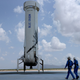 Four people walk towards the Blue Origin space craft